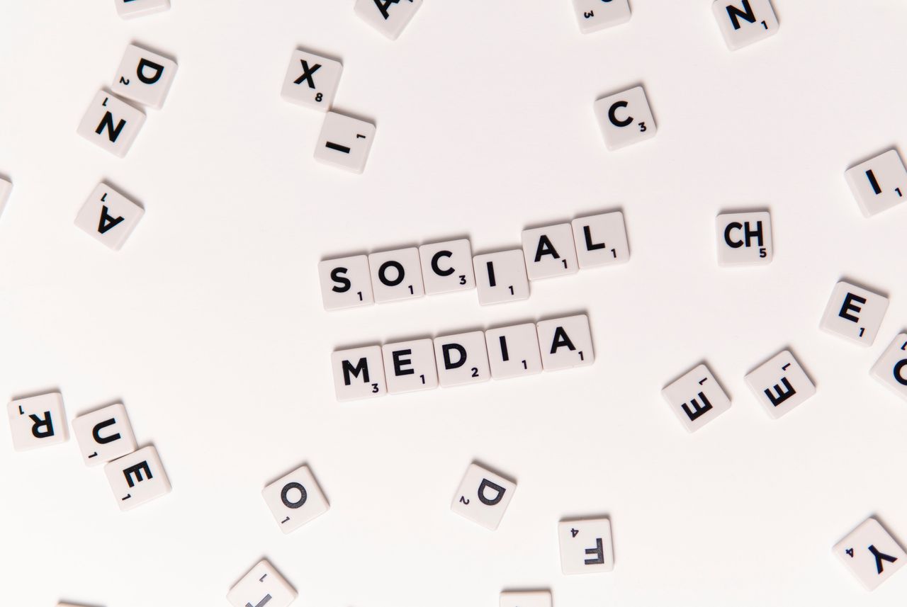 Flat lay of letter tiles spelling Social Media with scattered white tiles on a surface.